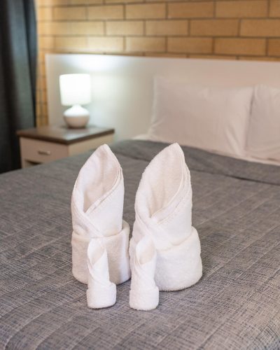 White folded towel on top of a comfortable bed in the Queen Single Room