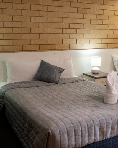 White folded towel on top of a comfortable bed in the Queen Single Room