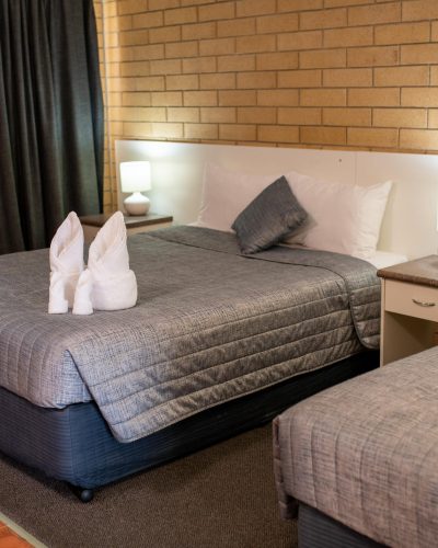 White folded towel on top of a comfortable bed in the Queen Single Room