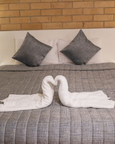 Comfortable grey bed with swan towels on top
