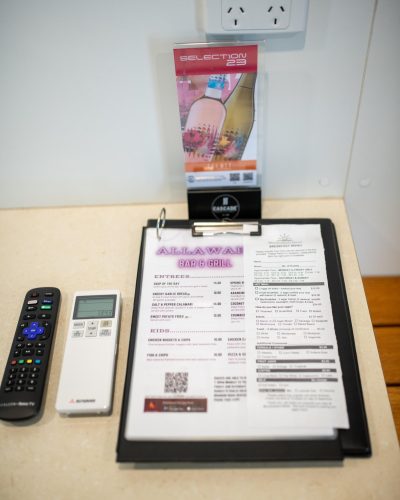 Allawah Bar & Grill Menu on top of the table beside remote controls